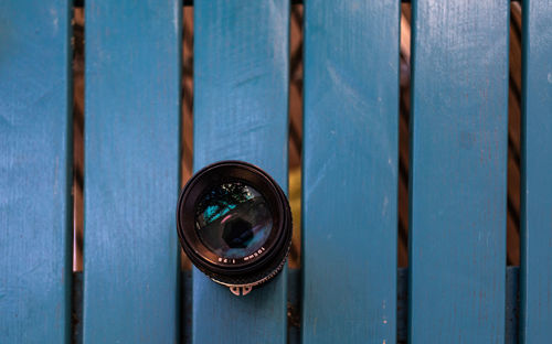 Directly above shot of camera lens on wooden bench