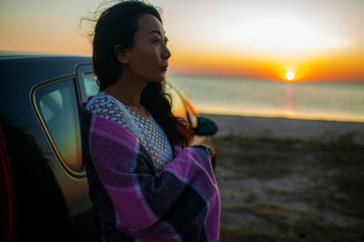 Young woman standing in car