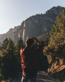 Rear view of person standing on rock against sky