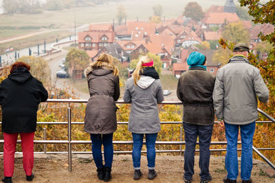 Rear view of people wearing warm clothing standing by railing