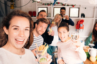 Portrait of friends with food and drinks enjoying in cottage during vacation