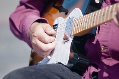 Midsection of man playing guitar