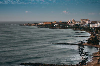 View of buildings by sea against cloudy sky