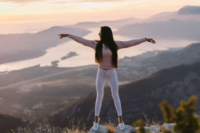 Rear view of woman standing on mountain against sky