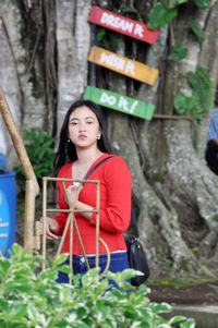 Woman looking away while standing against plants