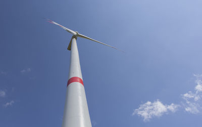 Wind turbine view with blades spinning around under a beautiful blue cloudy sky