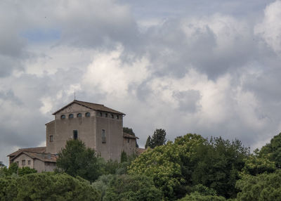 Low angle view of trees and building against sky