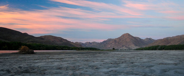 Scenic view of sea and mountains against sky during sunset