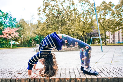 Girl playing with umbrella against trees