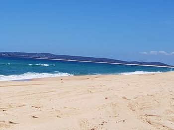 Scenic view of beach against clear blue sky