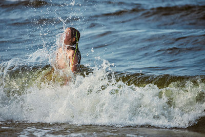 Low section of man surfing in sea