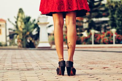 Low section of woman standing on footpath