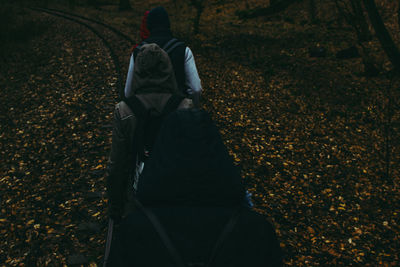 Rear view of people wearing hood walking in forest during autumn