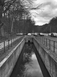 Footbridge over river against sky during winter