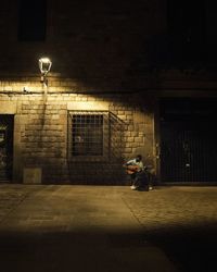 Illuminated street light on wall in city at night