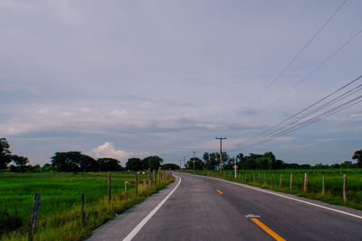 Road by trees against sky