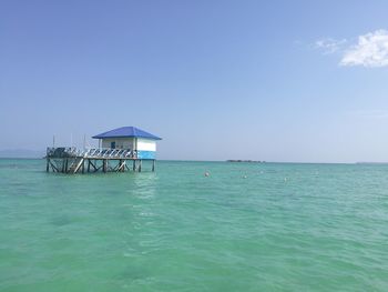 Lifeguard hut in sea against blue sky