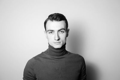 Portrait of young man wearing turtleneck t shirt against white background