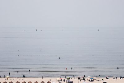 Group of people on beach against clear sky