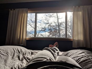 Low section of person relaxing on bed at home