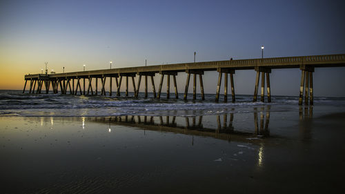 Pier over sea against sky during sunset