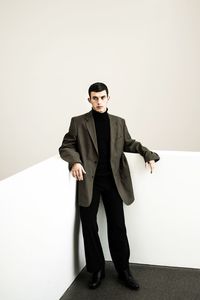 Portrait of young man standing against wall