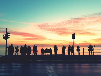 Silhouette people on promenade against sky during sunset