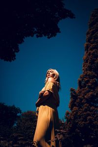 Low angle view of woman standing against blue sky