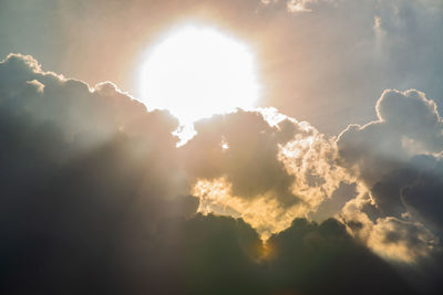 Low angle view of sunlight streaming through clouds