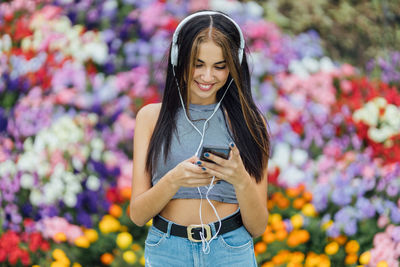 Portrait of smiling young woman standing on mobile phone