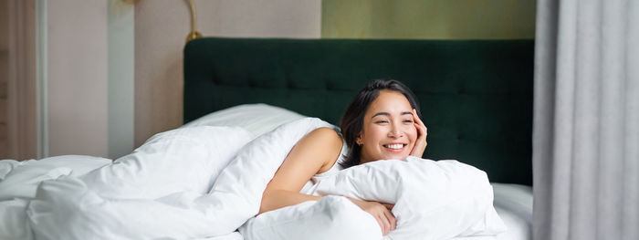 Young woman sitting on bed at home