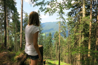 Rear view of woman standing in forest