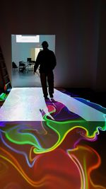 Full length rear view of man standing against illuminated stage