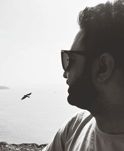 Portrait of man with seagull flying over sea against sky