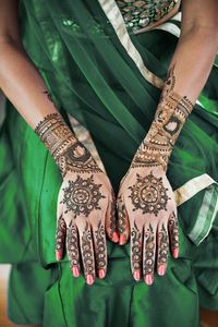 Midsection of woman showing heena tattoo on hand