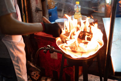 Midsection of man holding burning candles