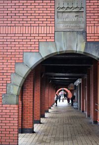 People walking on footpath under arched  building