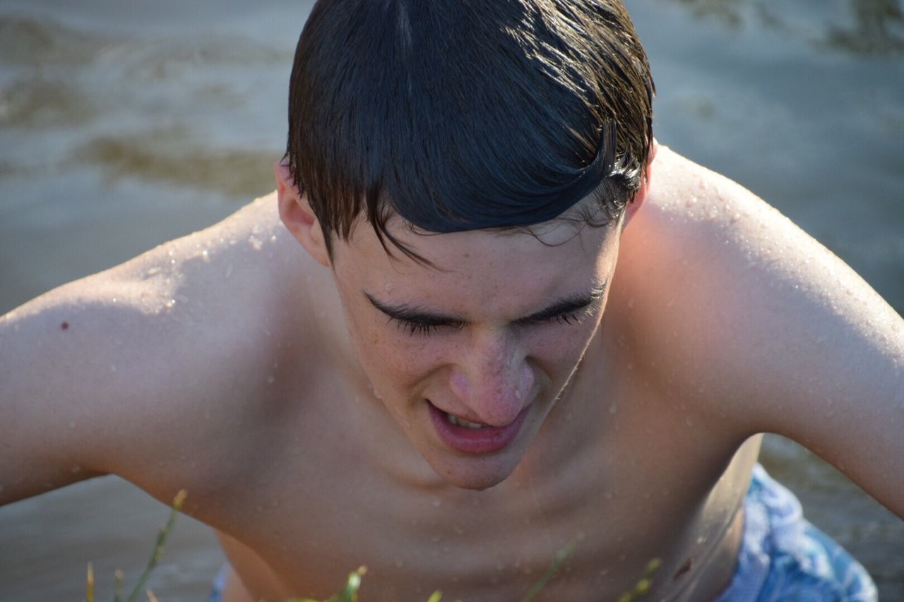 water, real people, one person, headshot, outdoors, lifestyles, leisure activity, focus on foreground, boys, young adult, day, wet, looking down, front view, elementary age, shirtless, nature, childhood, close-up