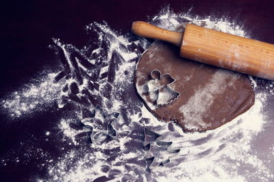 High angle view of cookie dough with rolling pin and flour on table