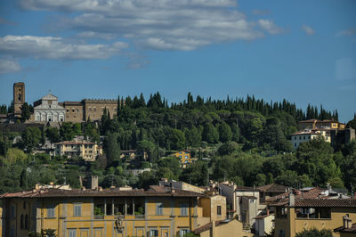 Houses and trees in city against sky