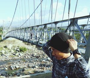 Man in hat against bridge against sky