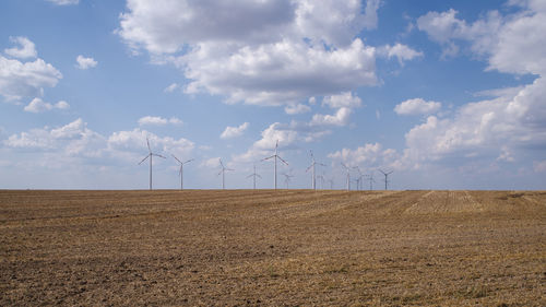 Windmills on field against sky