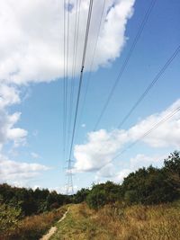 Low angle view of electricity pylon on field against sky