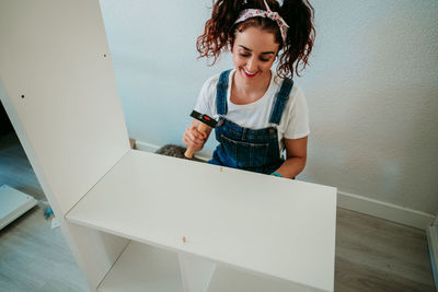 Smiling woman working over wood at home