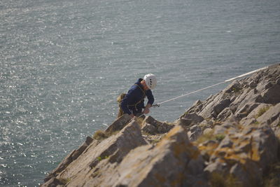 High angle view of man climbing on mountain against sea