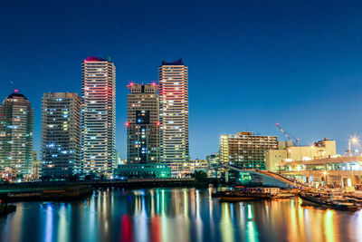 Illuminated buildings in city against clear sky at night