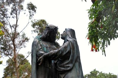 Low angle view of statue against trees against sky