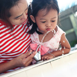 Low angle view of mother assisting daughter in drinking water through fountain