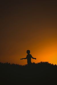 Silhouette man standing on field against sky during sunset