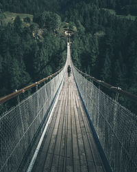 Rear view of young woman standing on suspension bridge